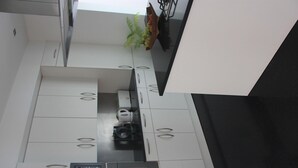 A modern kitchen with white cabinets, stainless steel appliances, and a black countertop. - Sea House Madeira - Atlantic Ocean (garajau)