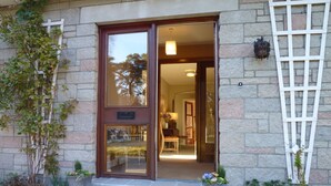 A building entrance with a stone facade, a wooden door, and a small porch area with potted plants. - Fabulous location, luxury lodge for 8+2 in cots, hot tub, garden, garage, dogs   (Aviemore)