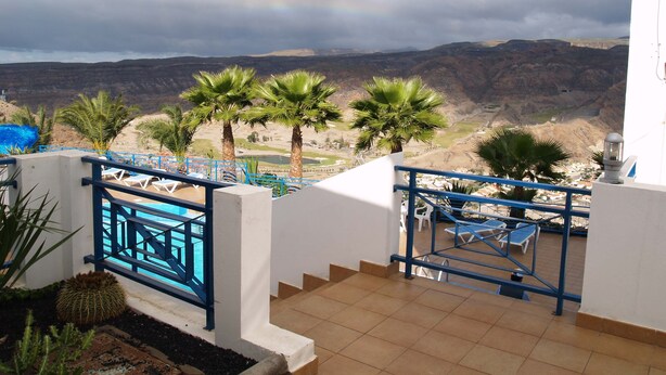 A terrace with a pool, palm trees, and a view of a valley. - Fantastic Views Amadores, Wifi (Mogán)