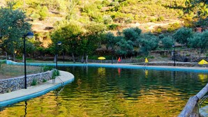 A swimming pool with a stone border, surrounded by trees and a hilly landscape. - Casas da Encosta, Shale Houses, Accommodation in Shale Village - Free Wifi (Sobreira Formosa)