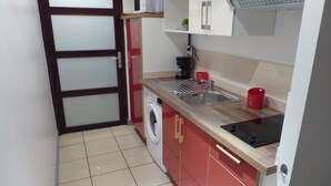 A compact kitchen with a washing machine, a sink, and a microwave. - Charming T2 in Boucan Canot - La Canotière du Boucan - 55 m² (Boucan Canot)