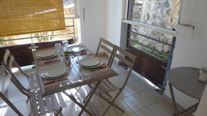 A dining area with a table set for four, including plates, glasses, and cutlery. - Charming T2 in Boucan Canot - La Canotière du Boucan - 55 m² (Boucan Canot)