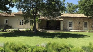 A two-story stone building with a tiled roof, a covered patio with outdoor seating, and a well-maintained lawn. - Beautiful Provence House in the Luberon - Heated Swimming Pool & Large Gardens. (Roussillon)