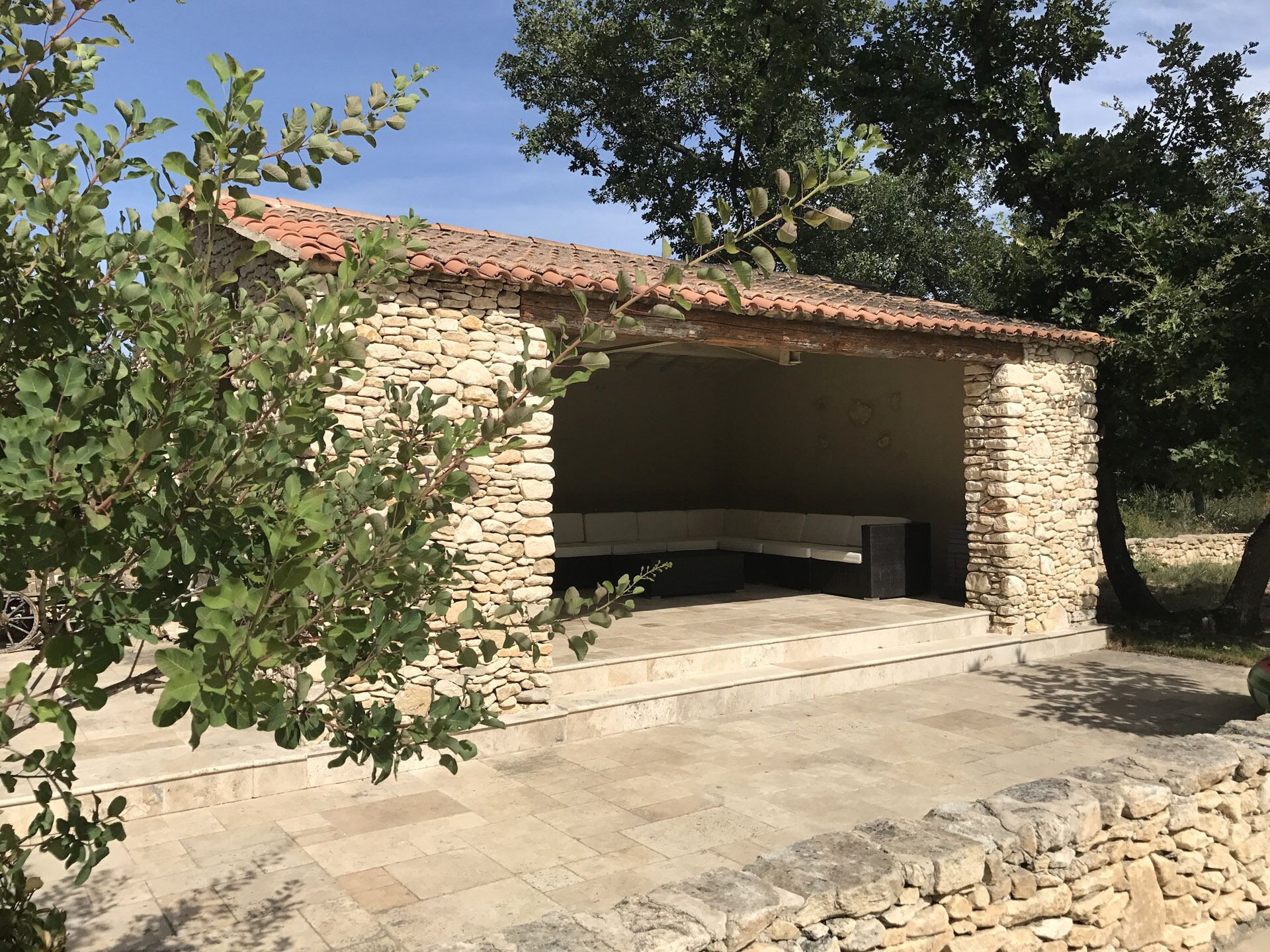 A stone building with a tiled roof, a stone bench, and a stone wall.