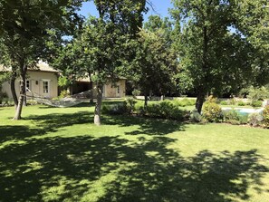A well-maintained garden with a hammock, a stone building, and a swimming pool. - Beautiful Provence House in the Luberon - Heated Swimming Pool & Large Gardens. (Roussillon)