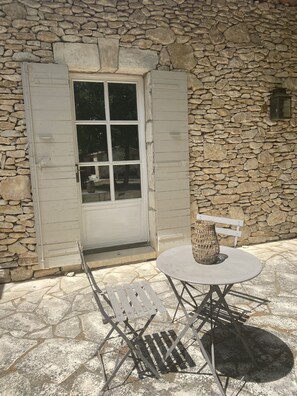A stone wall exterior with a white door and a small table with a wicker centerpiece. - Beautiful Provence House in the Luberon - Heated Swimming Pool & Large Gardens. (Roussillon)