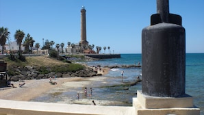 Ein Küstenstrand mit Leuchtturm und felsiger Küstenlinie.