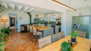 A spacious kitchen with modern appliances, a dining area with wooden furniture, and a visible clock on the wall. - Charming farmhouse with private heated pool and amazing mountain views. (Mont-De-Marrast)