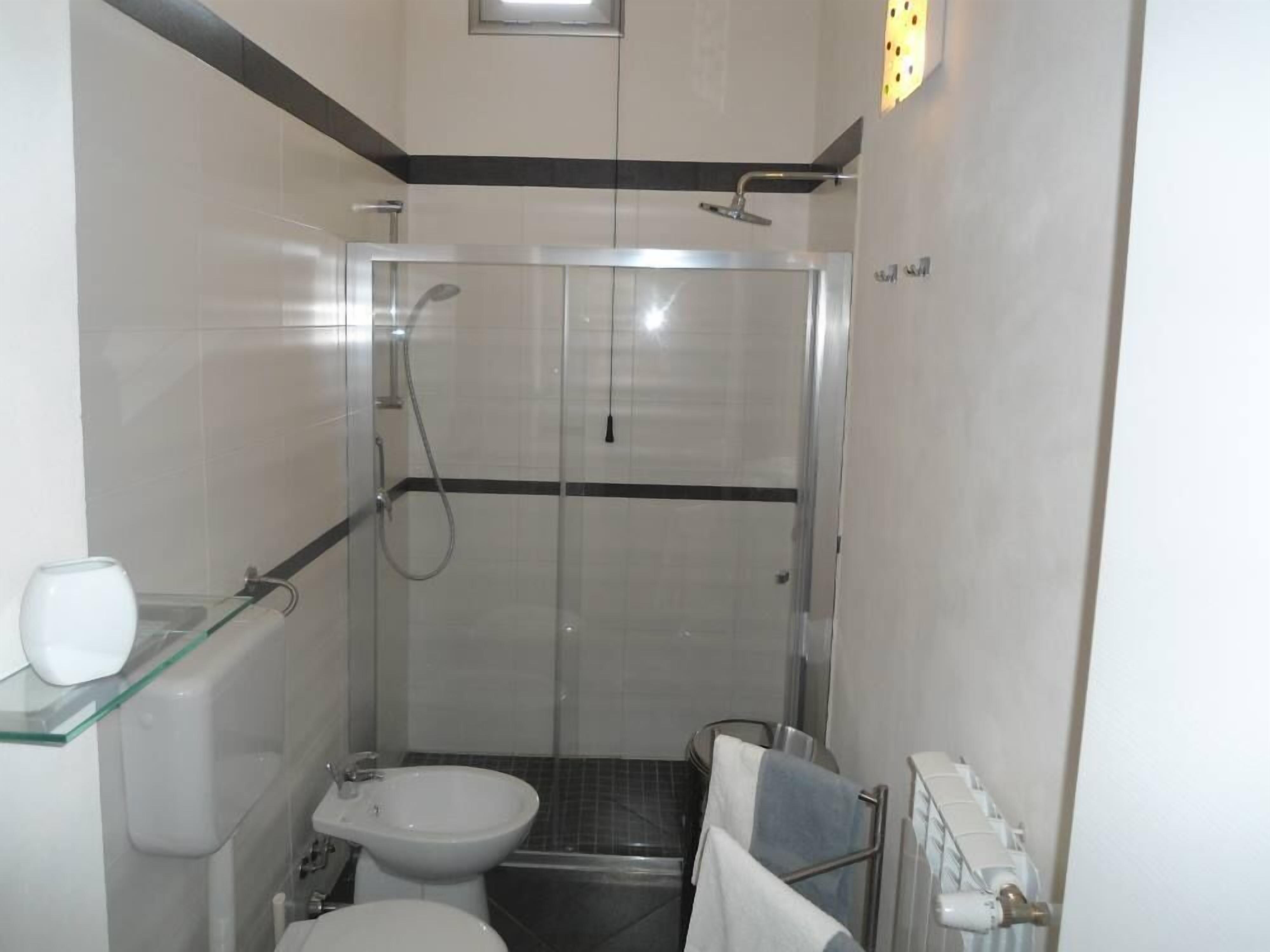 A compact bathroom with a glass-enclosed shower, a toilet, and a sink.