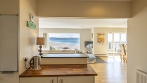 Eine moderne Küche mit einer Holz Arbeitsplatte, einem Wasserkocher und Meerblick durch große Fenster.