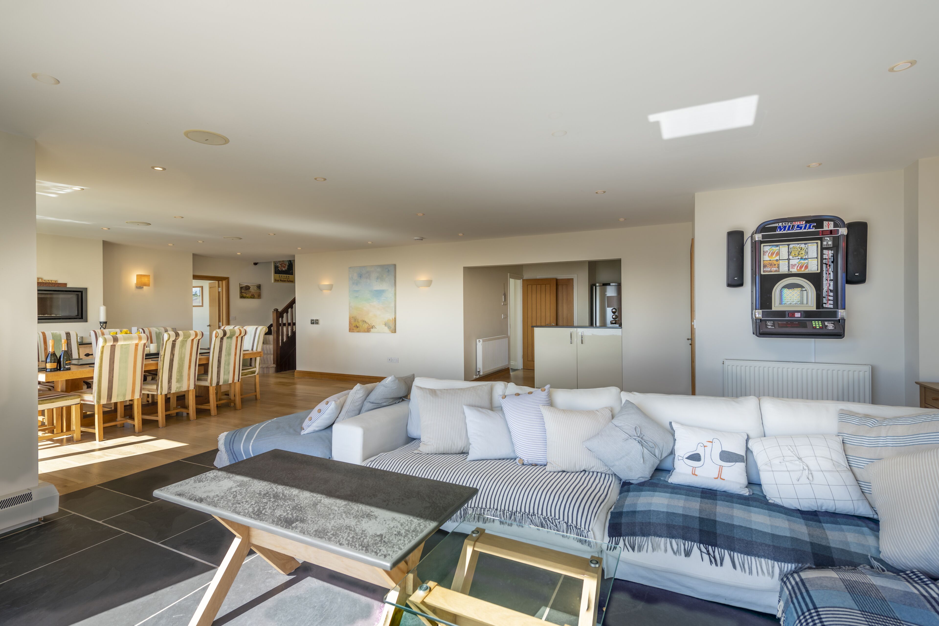 A spacious living area with a sofa, a coffee table, and a dining area with chairs and a table.