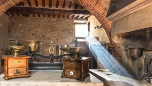 Una cocina de estilo antiguo con paredes de ladrillo, una encimera de madera y utensilios de cocina antiguos.