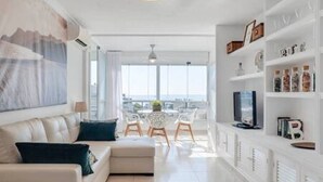 A modern living room with a sofa, a coffee table, and a TV. There is a balcony with a view. - COZY AND SPACIOUS APARTMENT - WELL LOCATED AND DIRECT SEA VIEW (Torremolinos)