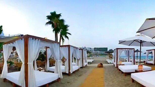 A beachside hotel with multiple white canopy beds arranged along a sandy walkway. - COZY AND SPACIOUS APARTMENT - WELL LOCATED AND DIRECT SEA VIEW (Torremolinos)