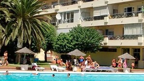 A swimming pool area with lounge chairs and umbrellas, surrounded by a multi-story building with balconies. - COZY AND SPACIOUS APARTMENT - WELL LOCATED AND DIRECT SEA VIEW (Torremolinos)