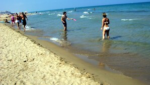 Une plage où l’on voit des gens se promener et jouer dans l’eau.