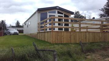 A mobile home with a wooden deck and a fenced yard.