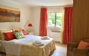 A hotel room with a bed, a chair, a window with curtains, a radiator, and a painting on the wall. - Beautiful Villa with amazing views and private pool!! (Vilamoura)