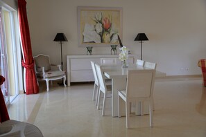 Ein Essbereich mit weißem Tisch und Stühlen, einem Gemälde an der Wand und zwei Stehlampen.