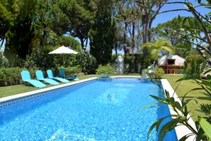 A swimming pool with clear blue water, surrounded by green trees and a white umbrella. - Beautiful Villa with amazing views and private pool!! (Vilamoura)