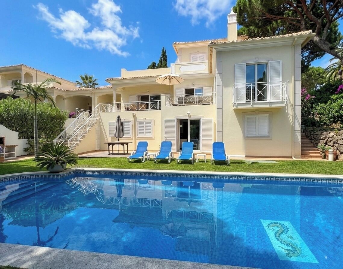 A two-story building with a swimming pool, outdoor seating, and a staircase leading to the entrance.
