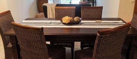 A dining area with a dark wooden table, wicker chairs, and a decorative centerpiece.