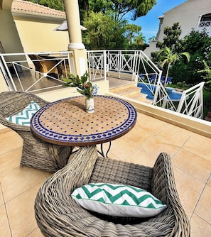 A patio area with wicker furniture, a tiled table, and a view of a swimming pool.