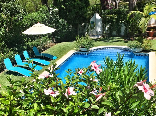 A swimming pool surrounded by a well-maintained garden with blue lounge chairs and a statue. - Beautiful Villa with amazing views and private pool!! (Vilamoura)