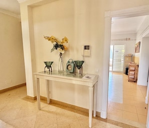 A hallway with a white console table, a wall-mounted phone, and a door leading to another room.