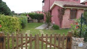 A pink house with a stone wall, a wooden gate, and a stone path leading to the entrance. - VILLETTA TO FORMATION WITH GARDEN 300MT FROM THE SEA (Pittulongu)