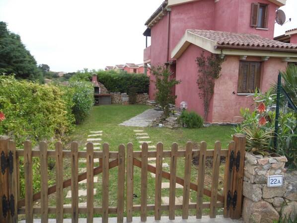A pink house with a stone wall, a wooden gate, and a stone path leading to the entrance. - VILLETTA TO FORMATION WITH GARDEN 300MT FROM THE SEA (Pittulongu)