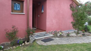 A pink building with a small entrance, a window, and a garden with plants and a lamp post. - VILLETTA TO FORMATION WITH GARDEN 300MT FROM THE SEA (Pittulongu)