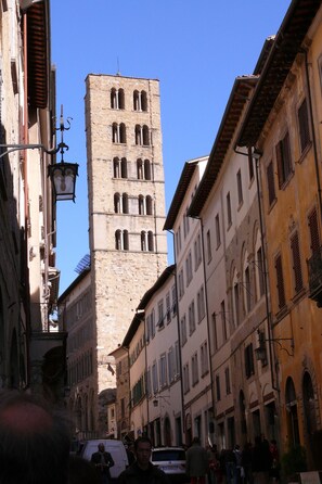 A narrow street with historic buildings, a prominent tower, and a white van.