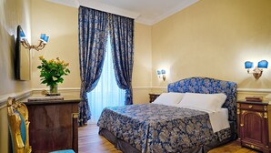 A hotel room with a large bed, a desk with a vase of flowers, and a chair.