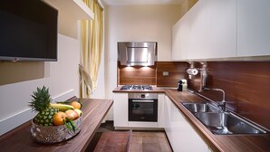 A modern kitchen with a built-in oven, a stainless steel sink, and a flat-screen TV mounted on the wall.