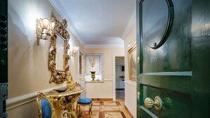 A hallway with ornate gold furniture, a green door, and a patterned floor.