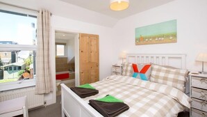A bedroom with a bed, a window, a door, a painting, and a bedside table. - Goodwin Sands Cottage - 50 meters from the beach  (Deal)