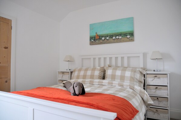 A bedroom with a bed, two nightstands, a painting, and a wooden door.