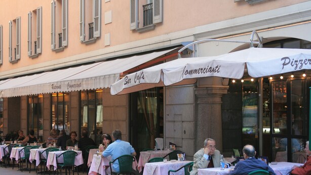 An outdoor cafe with tables and chairs, some with umbrellas. - Stunning views - Beautiful holiday home in a friendly Italian village  (Dumenza (VA))