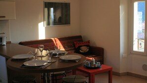 A compact living space with a dining area, a sofa with a 'MOCHA' pillow, and a window with a view of buildings. - Stunning views - Beautiful holiday home in a friendly Italian village  (Dumenza (VA))