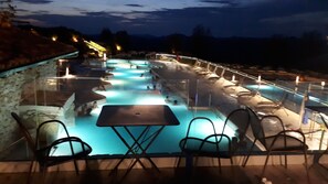 Zona de piscina con varias pistas, sillas y mesas.