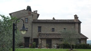 A stone building with a tiled roof, a small balcony, and a lamp post.