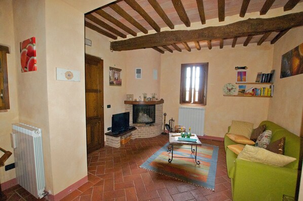 Una sala de estar acogedora con chimenea, un sofá verde y un televisor.