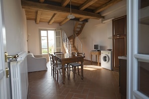A spacious kitchen with a wooden staircase, a dining table with chairs, and a washing machine.