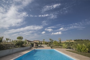 A swimming pool with a clear sky and distant houses.