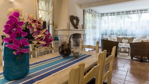 A dining area with a wooden table, chairs, and a vase of flowers.
