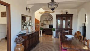 Un vaste espace dédié à la salle à manger, avec une grande table et des chaises en bois, un lustre et un miroir décoratif.