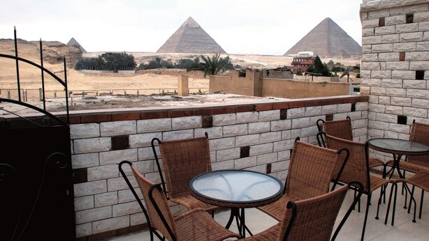 A terrace with wicker chairs and a glass table, overlooking the pyramids. - Beautiful view of the Pyramids, with air conditioning, WiFi, and touristic guide (Cairo)