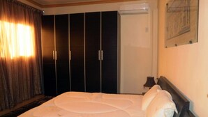A hotel room with a large bed, dark wardrobe, and a painting on the wall. - Beautiful view of the Pyramids, with air conditioning, WiFi, and touristic guide (Cairo)