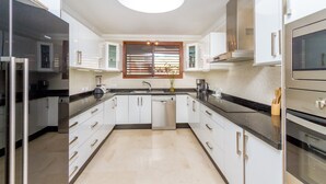Een moderne keuken met witte kastjes, een zwart aanrecht en roestvrijstalen apparatuur.